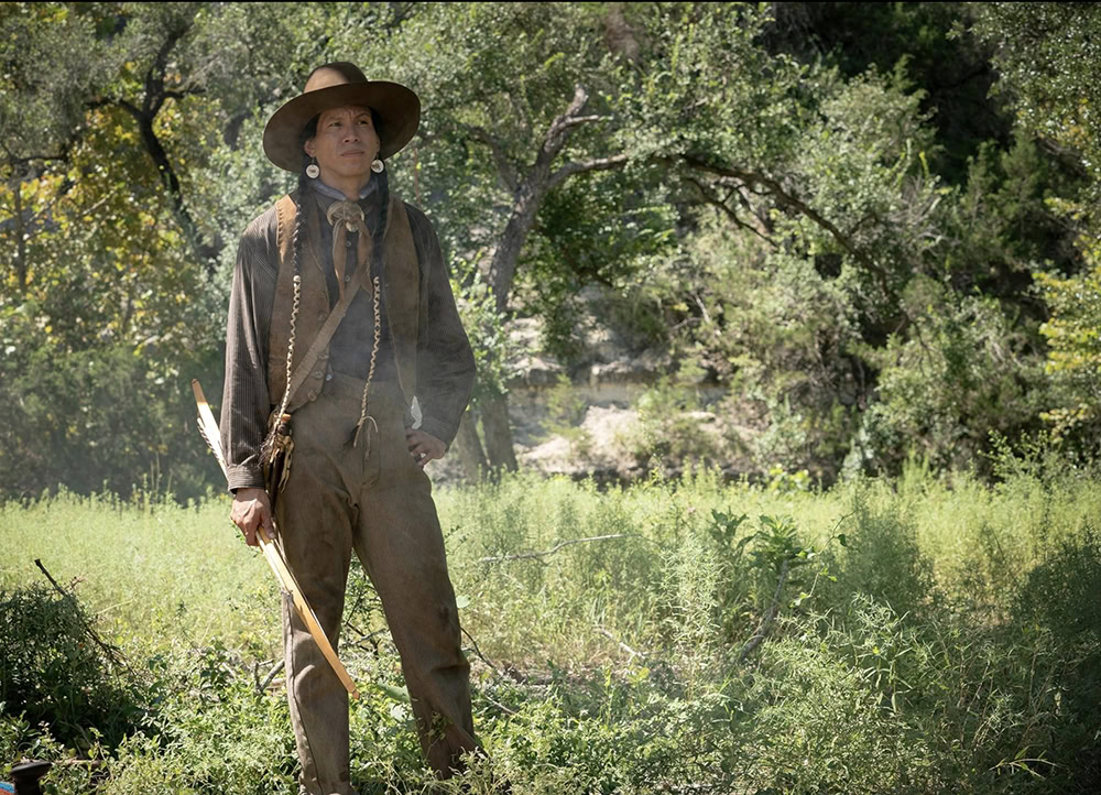 A man stands in period clothing set in 1923.