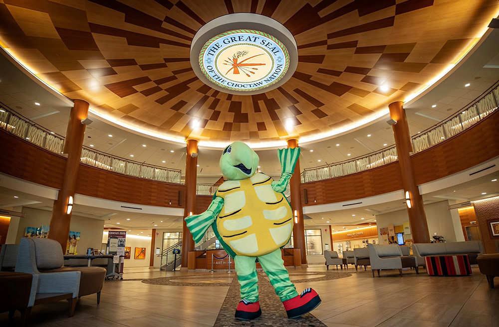 A person wearing a costume of Luksi the turtle.