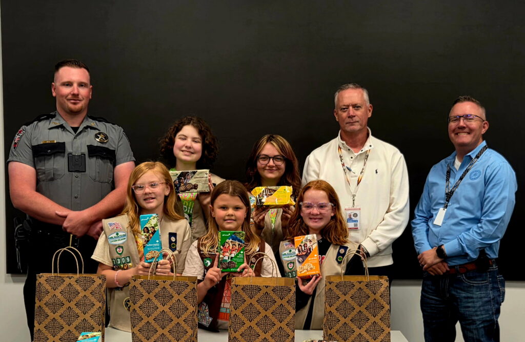 Several policeman and Girls Scouts pose for a photo together.