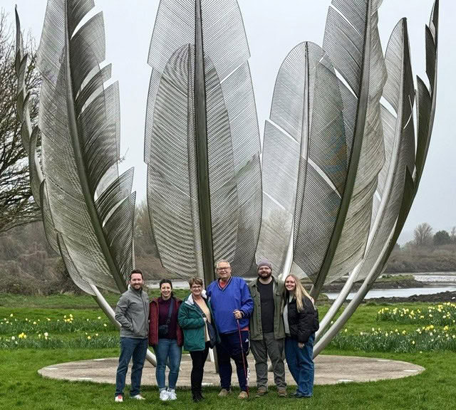 A group of people pose for a photo in front of the Kindred Spirits monument.