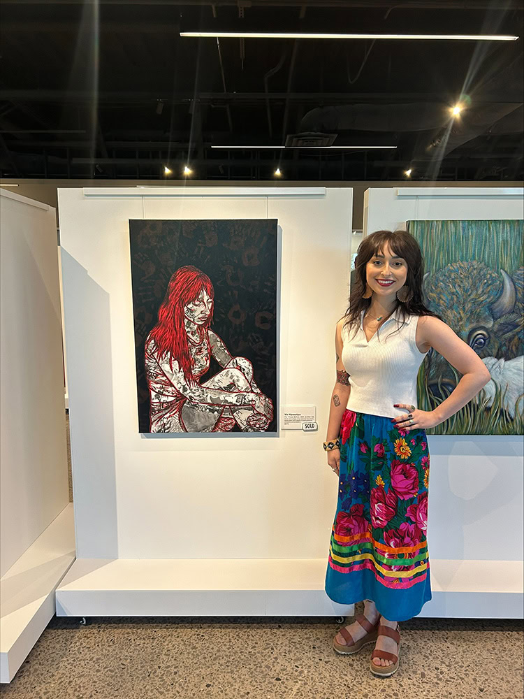 A woman poses for a photo next to a painting.