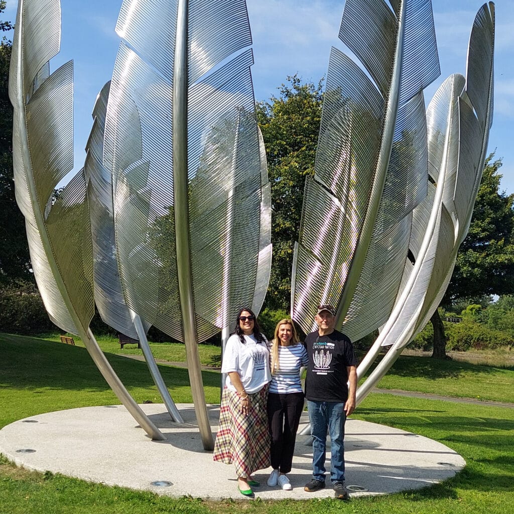 Three people stand in front of the Kindred Spirits monument.