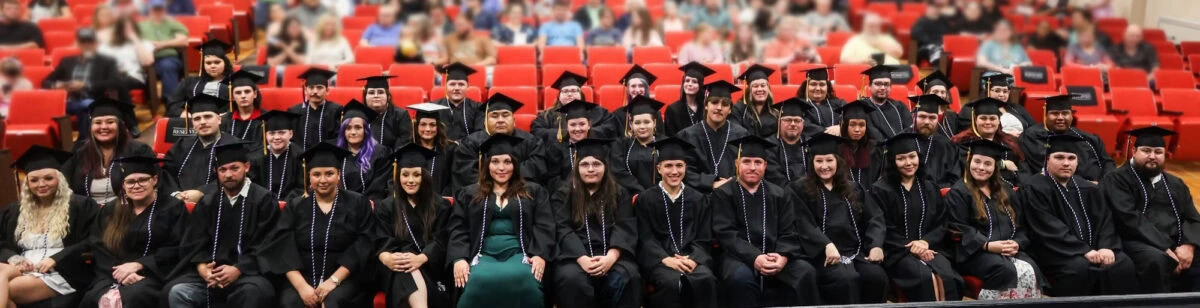 A large group of adults pose for a photo wearing graduation cap and gowns.