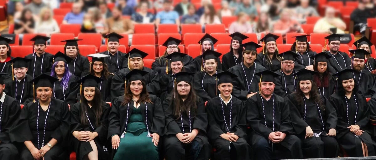 A large group of adults pose for a photo wearing graduation cap and gowns.
