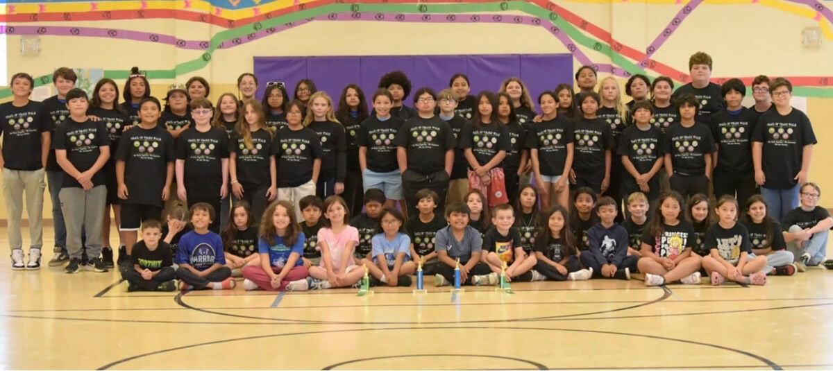 A large group of students pose for a photo in a gymnasium.