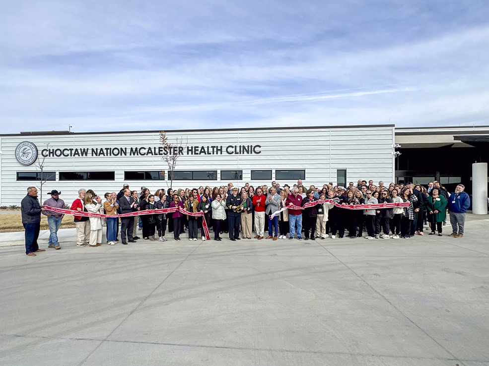 A large group of people pose for a photo during a ribbon cutting ceremoby.