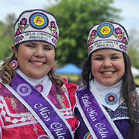 To young women pose for a photo wearing princess regalia.