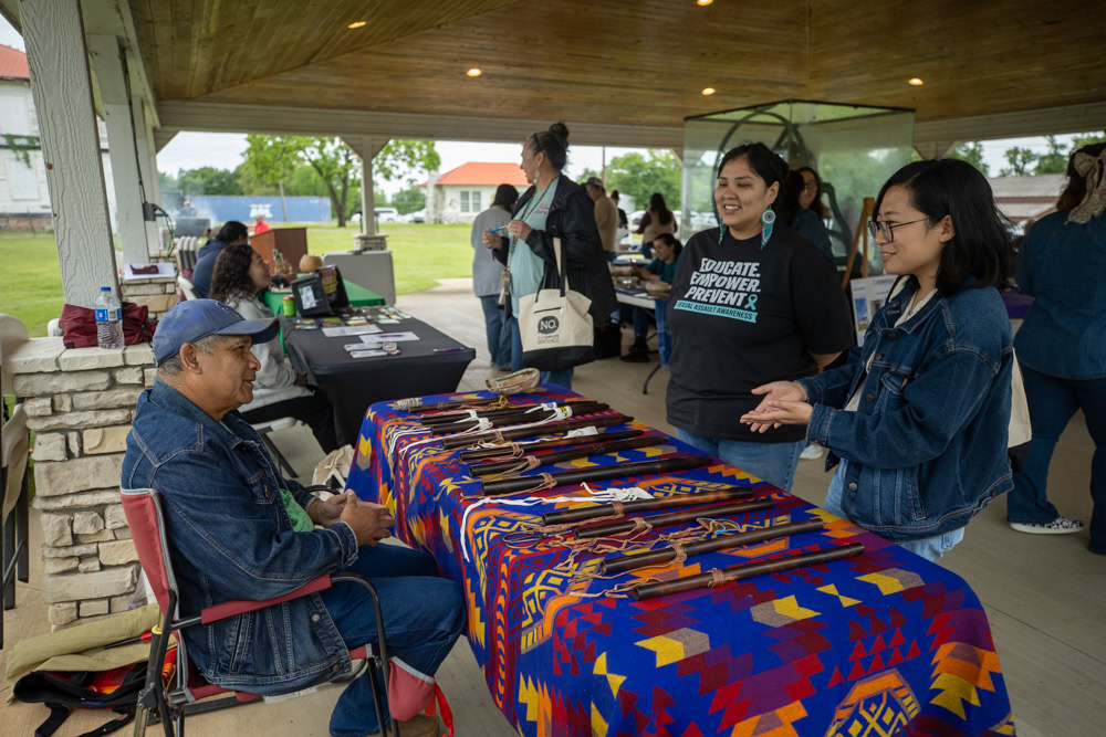Two women visit with a an at an information booth. 