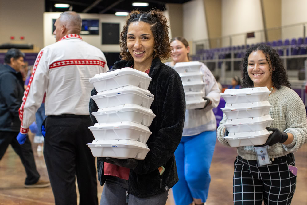 Two women pass out meals.