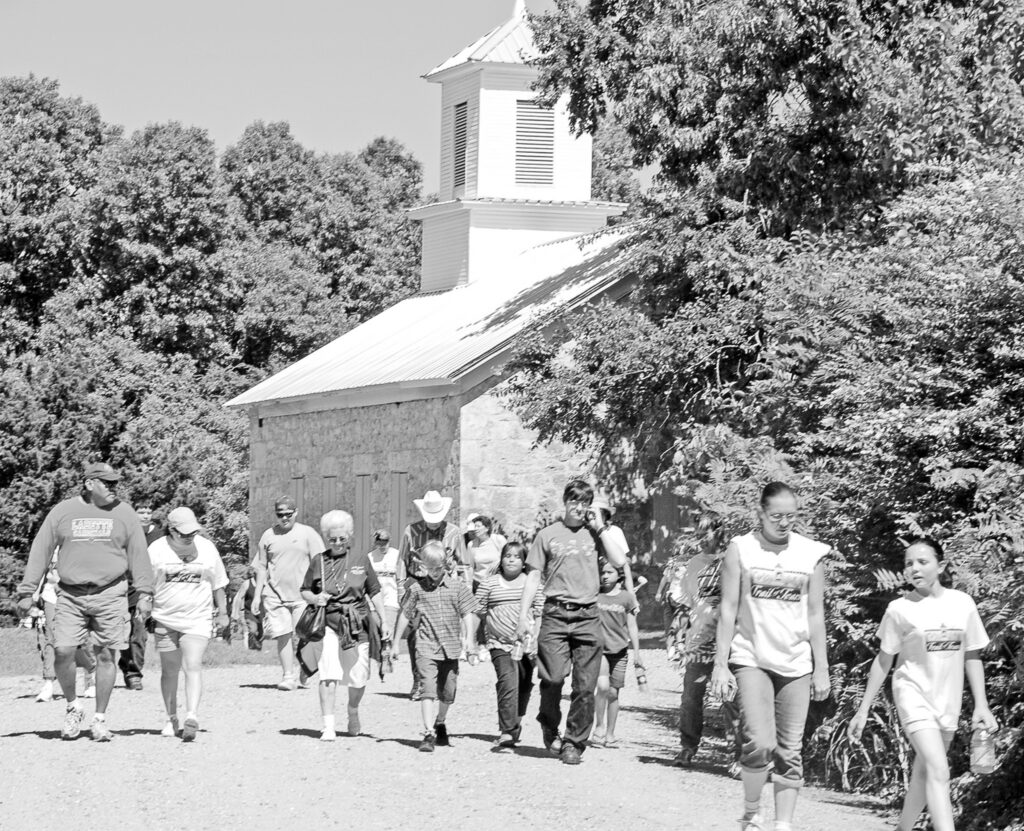 A large group of people walk past a chruch.