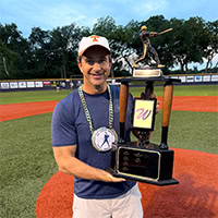A young man poses for a photo while holding a trophy.