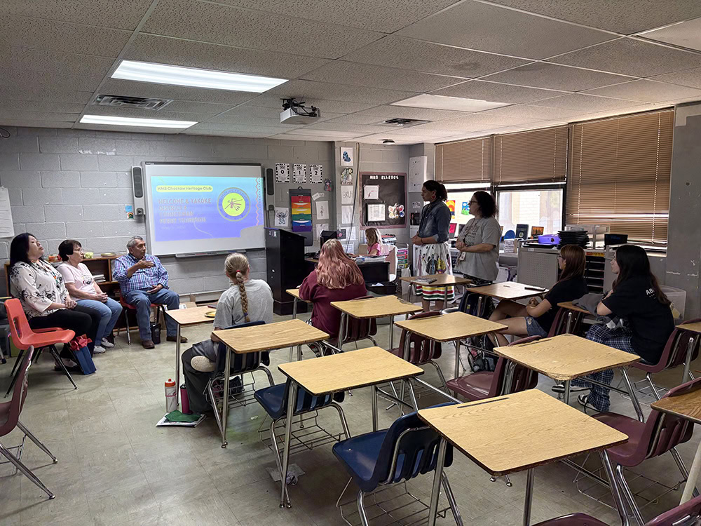 People in a classroom watch a presentation projected on a screen.
