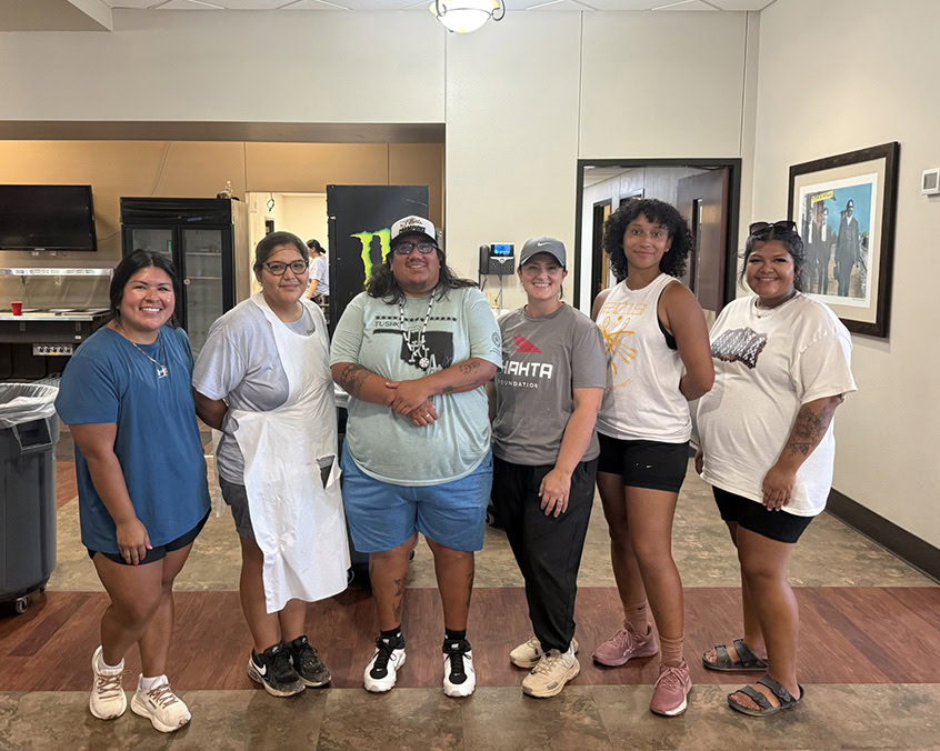 A group of five people poses for a photo in a cafeteria. 