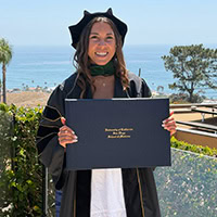A woman poses for a photo holding a graduation certificate.