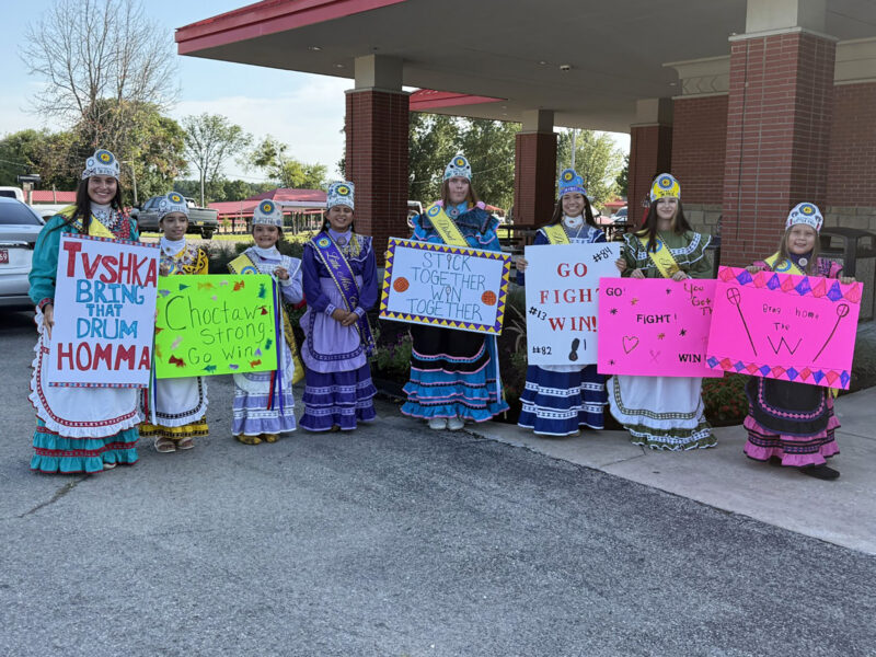 Choctaw princesses hold up signs.