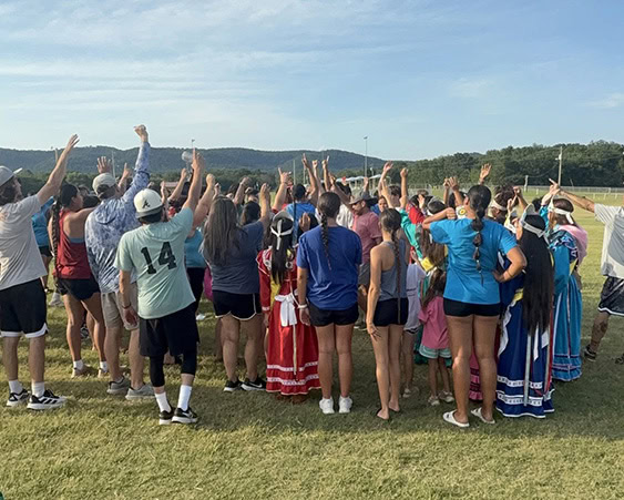 Stickball players raise their sticks in the air.