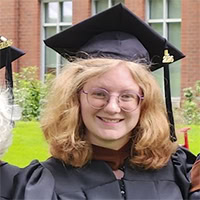A woman poses for a photo wearing graduation regalia