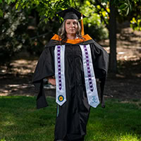 A woman poses for a photo wearing graduation regalia.