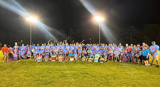 A large stickball team poses for a photo.