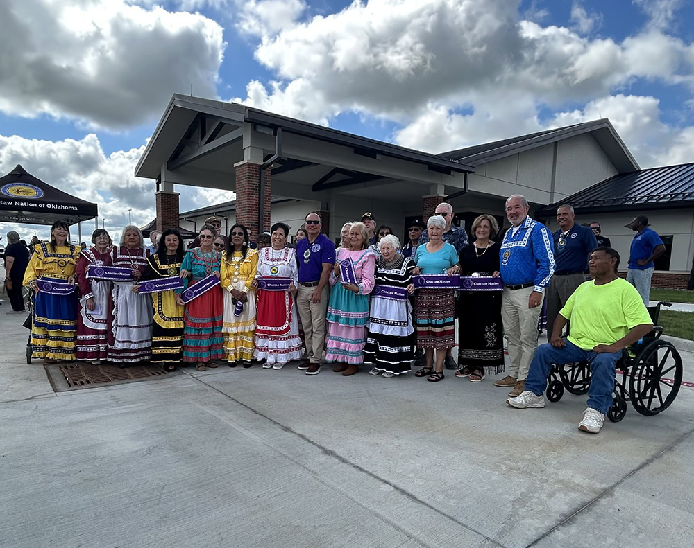 A large group of people pose for a photo in front of a building.