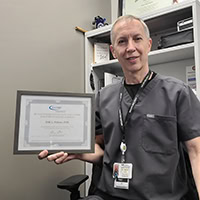 A man poses for a photo holding a certificate.