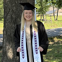 A woman poses for a photo wearing graduation regalia.