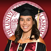 A woman poses for a photo wearing graduation regalia.
