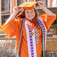 A woman poses for a photo wearing graduation regalia.