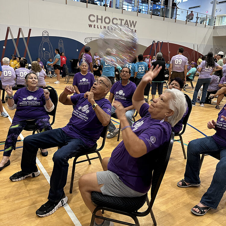 Elders play volleyball while sitting in chairs.