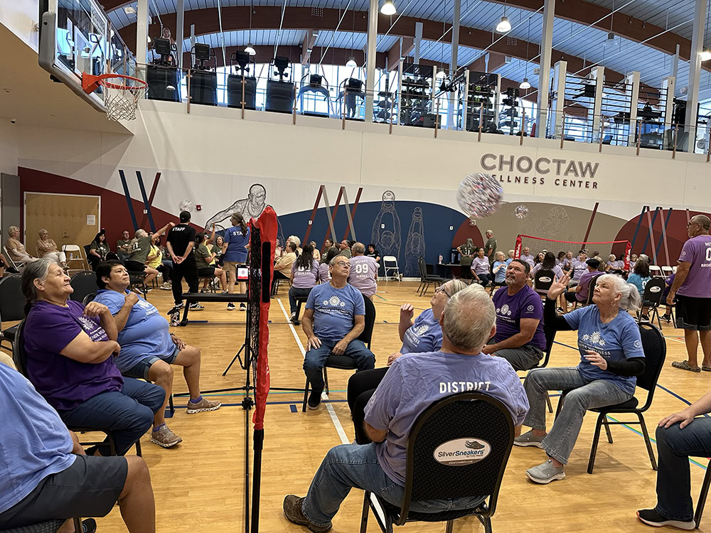 Elders play volleyball while sitting in chairs.