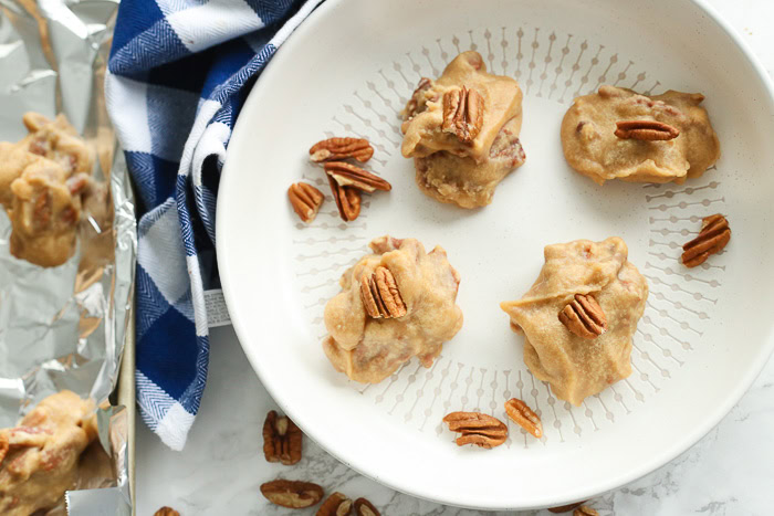 pecan parlines in white dish with pralines on tin foil off to side