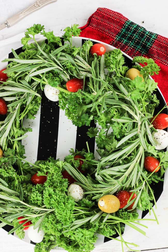 This holiday olive wreath is a festive holiday appetizer that is not only easy to put together, put easily adaptable to the party-goers likes and needs. Plate your favorite herbs underneath tasty mozzarella cheese, sweet tomatoes, and your favorite olives. Sprinkle cracked pepper and a delicious balsamic drizzle to finish! www.blessherheartyall.com