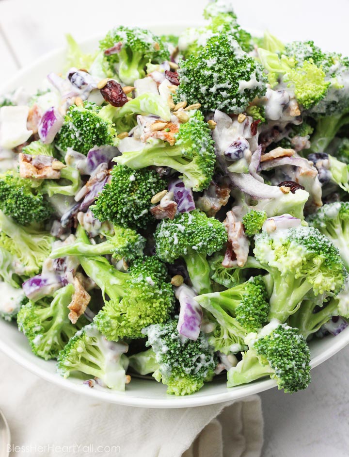 This skinny greek yogurt broccoli salad is a simple veggie dish that combines fresh broccoli spears, dried cranberries, and a sweet creamy dressing made with greek yogurt! It's the perfect healthy side dish to any winter meal! www.blessherheartyall.com