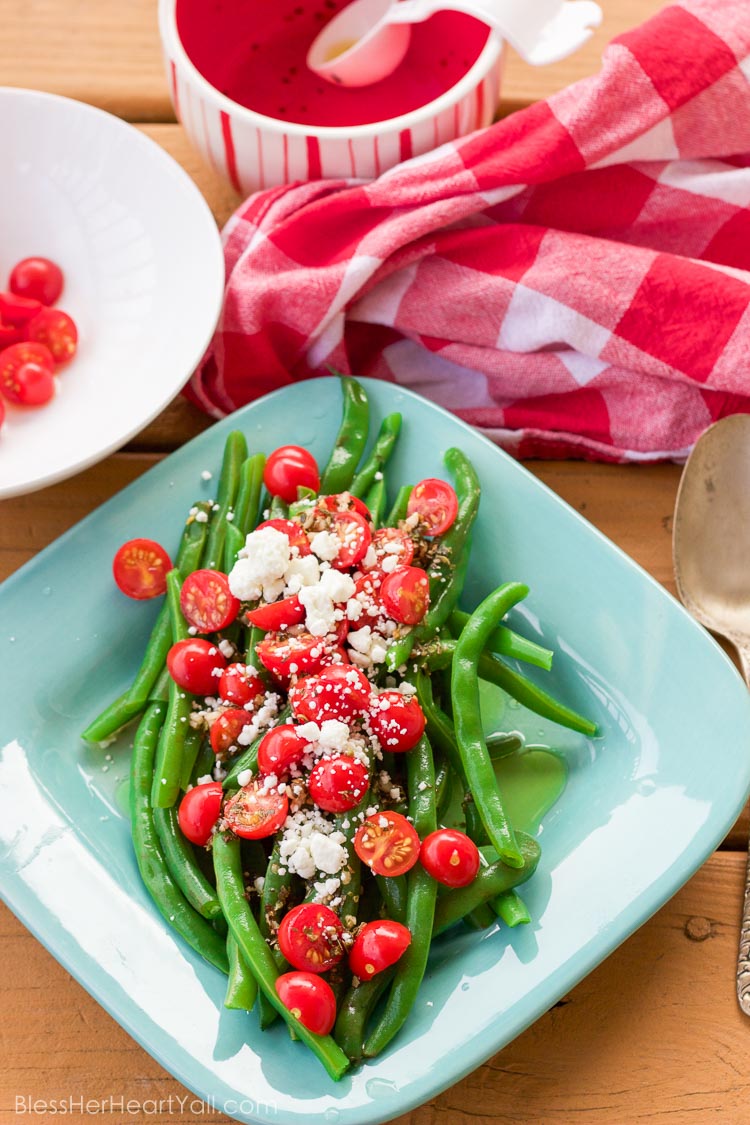 These 5 minute greek green beans use fresh cooked green beans that are drizzled with a quick homemade greek dressing and topped with fresh tomato and feta cheese crumbles. They are great served warm or cold and are perfect for all those summer parties!