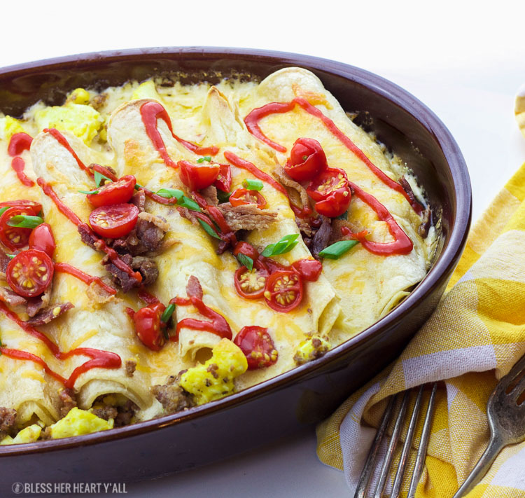 This delicious recipe for gluten-free breakfast enchiladas will wake anyone's taste buds up for the day! The combination of fluffy eggs and spicy breakfast sausage wrapped in corn tortillas and then topped with a seasoned cheese drizzle, baked and then loaded with fresh veggie chunks and bacon crumbles will make anyone's morning sunny!