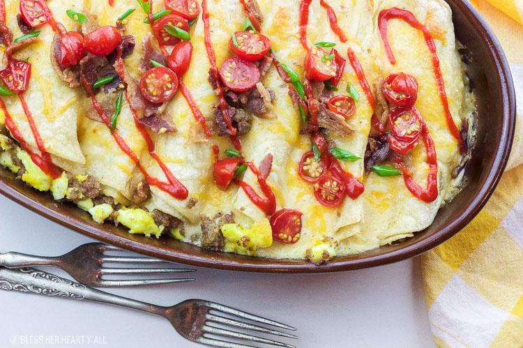 This delicious recipe for gluten-free breakfast enchiladas will wake anyone's taste buds up for the day! The combination of fluffy eggs and spicy breakfast sausage wrapped in corn tortillas and then topped with a seasoned cheese drizzle, baked and then loaded with fresh veggie chunks and bacon crumbles will make anyone's morning sunny!