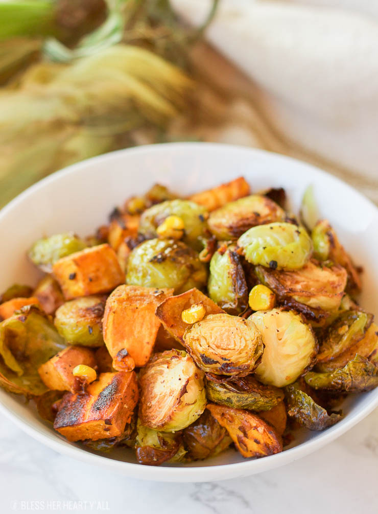 This healthy roasted sweet potato brussel sprout hash is a simple fall treat that drizzles on a light layer of olive oil, garlic, and cumin before roasting. The vegan and gluten-free recipe produces perfectly golden baked sweet potato pieces surrounded by fresh spiced corn kernels and crisp and tender cooked brussel sprouts.