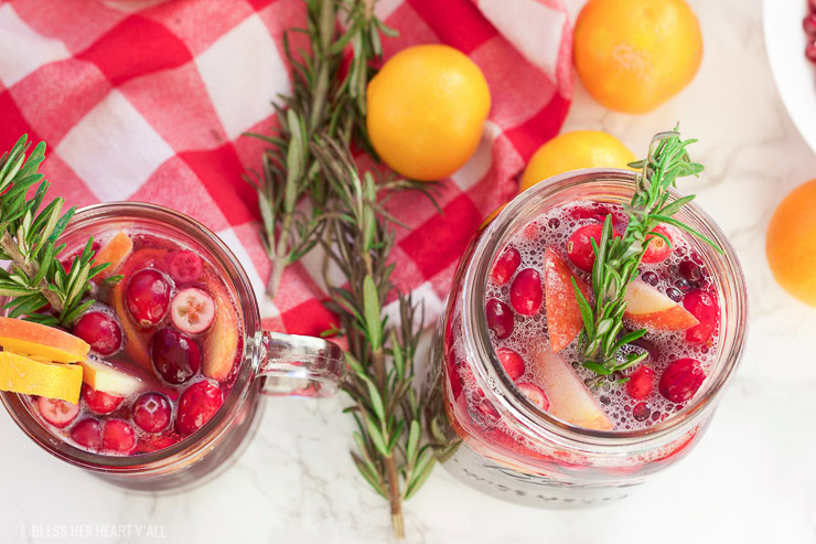 This winter pomegranate cranberry sangria recipe is a quick and easy twist on the popular sangria drink. Impress everyone at your next holiday or Christmas party with this sparkling red wine cocktail with apples, oranges, pomegranate, cranberry, rosemary, and cinnamon sticks! Get your drink on fancy pants!