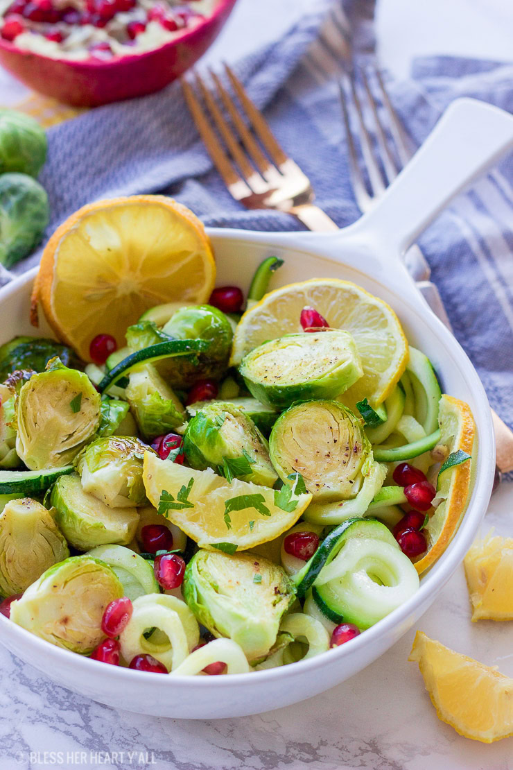 This lemon garlic roasted brussel sprouts + zucchini recipe is a clean, crisp, savory vegetable dish that is not only healthy but a gorgeous and easy addition to any meal! Lemon, honey, and garlic flavors coat the roasted brussel sprouts, zucchini noodles, and pomegranate arils for a colorful fresh salad.