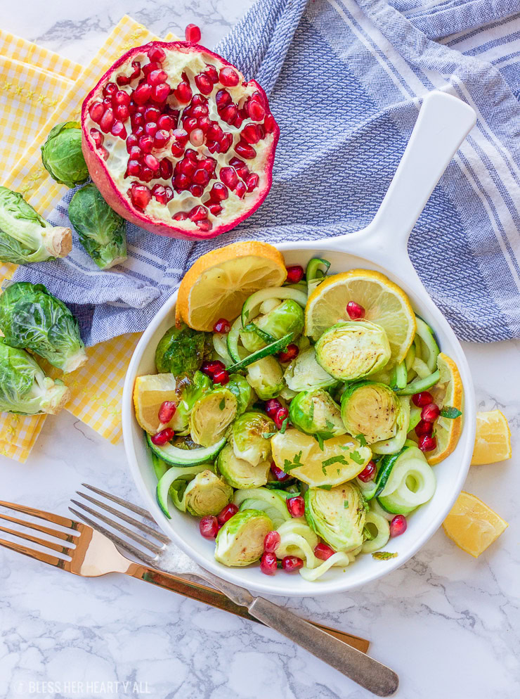 This lemon garlic roasted brussel sprouts + zucchini recipe is a clean, crisp, savory vegetable dish that is not only healthy but a gorgeous and easy addition to any meal! Lemon, honey, and garlic flavors coat the roasted brussel sprouts, zucchini noodles, and pomegranate arils for a colorful fresh salad.