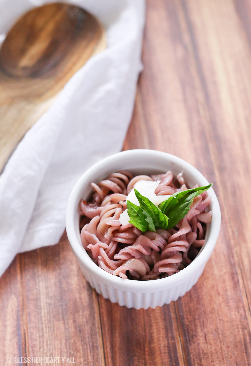 This gluten free red wine pasta + garlic basil goat cheese sauce is the perfect quick and fancy date night recipe that's ready in under 20 minutes! The pasta is cooked and stained in red wine and then tossed in a creamy garlic basil goat cheese sauce.