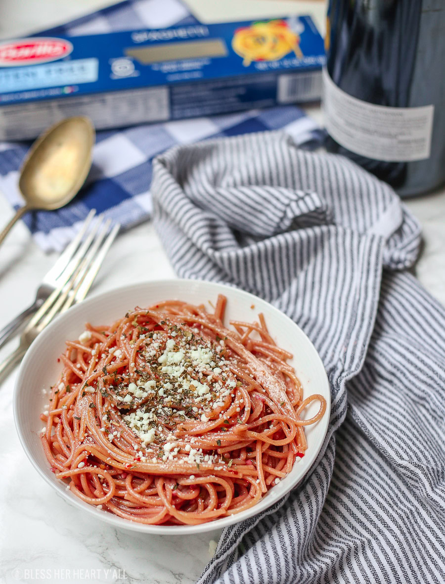 This gluten free red wine pasta + garlic basil goat cheese sauce is the perfect quick and fancy date night recipe that's ready in under 20 minutes! The gluten free pasta is cooked and stained in red wine and then tossed in a creamy garlic basil goat cheese sauce.