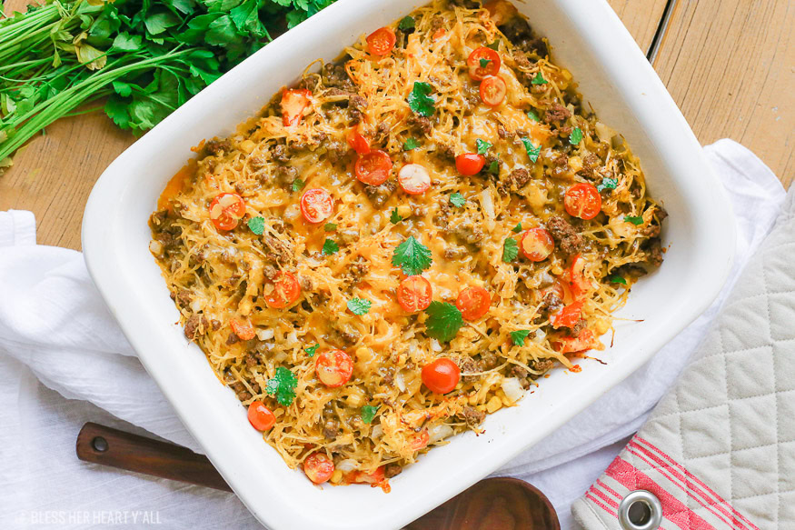 Spaghetti squash taco bake roasts fluffy spaghetti squash and melts it into seasoned ground meat, tomatoes, onion, corn, beans, and tops it off with melty cheese and fresh cilantro for the perfect healthy taco-inspired casserole!