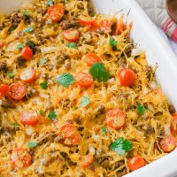 Spaghetti squash taco bake roasts fluffy spaghetti squash and melts it into seasoned ground meat, tomatoes, onion, corn, beans, and tops it off with melty cheese and fresh cilantro for the perfect healthy taco-inspired casserole!