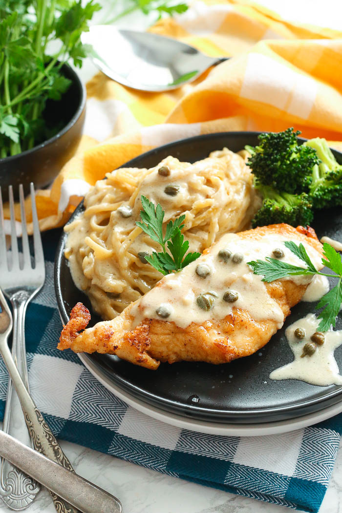 creamy instant pot chicken piccata that is gluten-free with pasta in black bowl with herbs