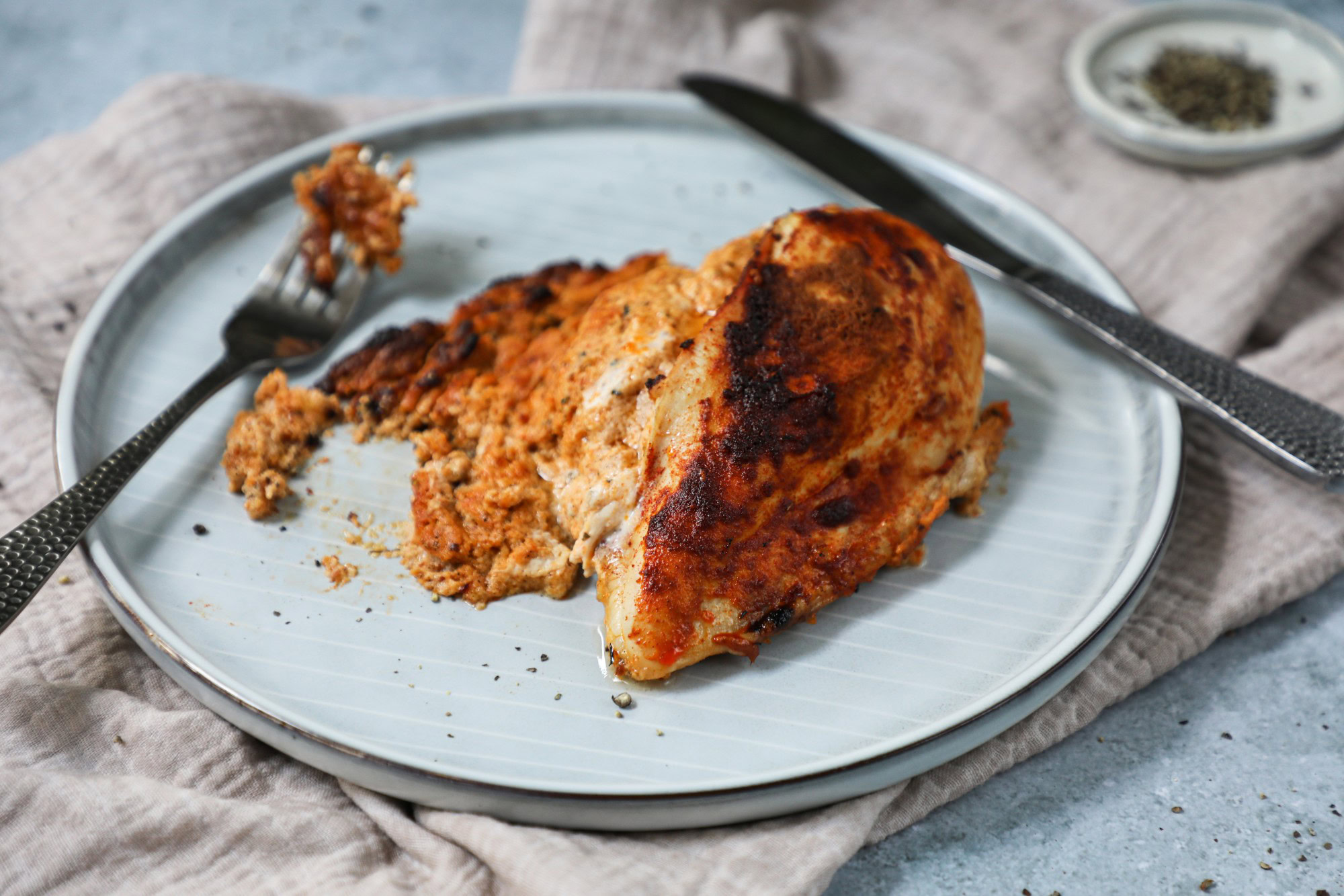 Chicken breast, knife and fork on a grey plate