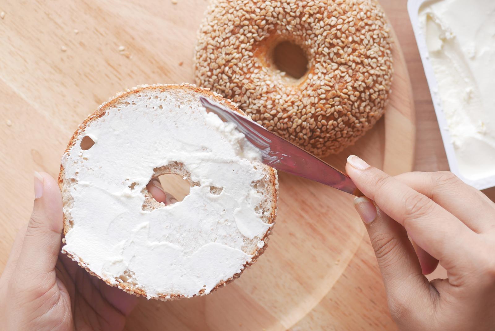 cheese cream spread on fresh bagel bread .