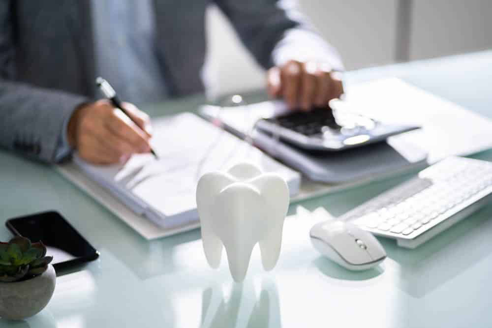 Business Person sitting at desk. Papers all around. Holding a pen and using a calculator, tooth on desk.