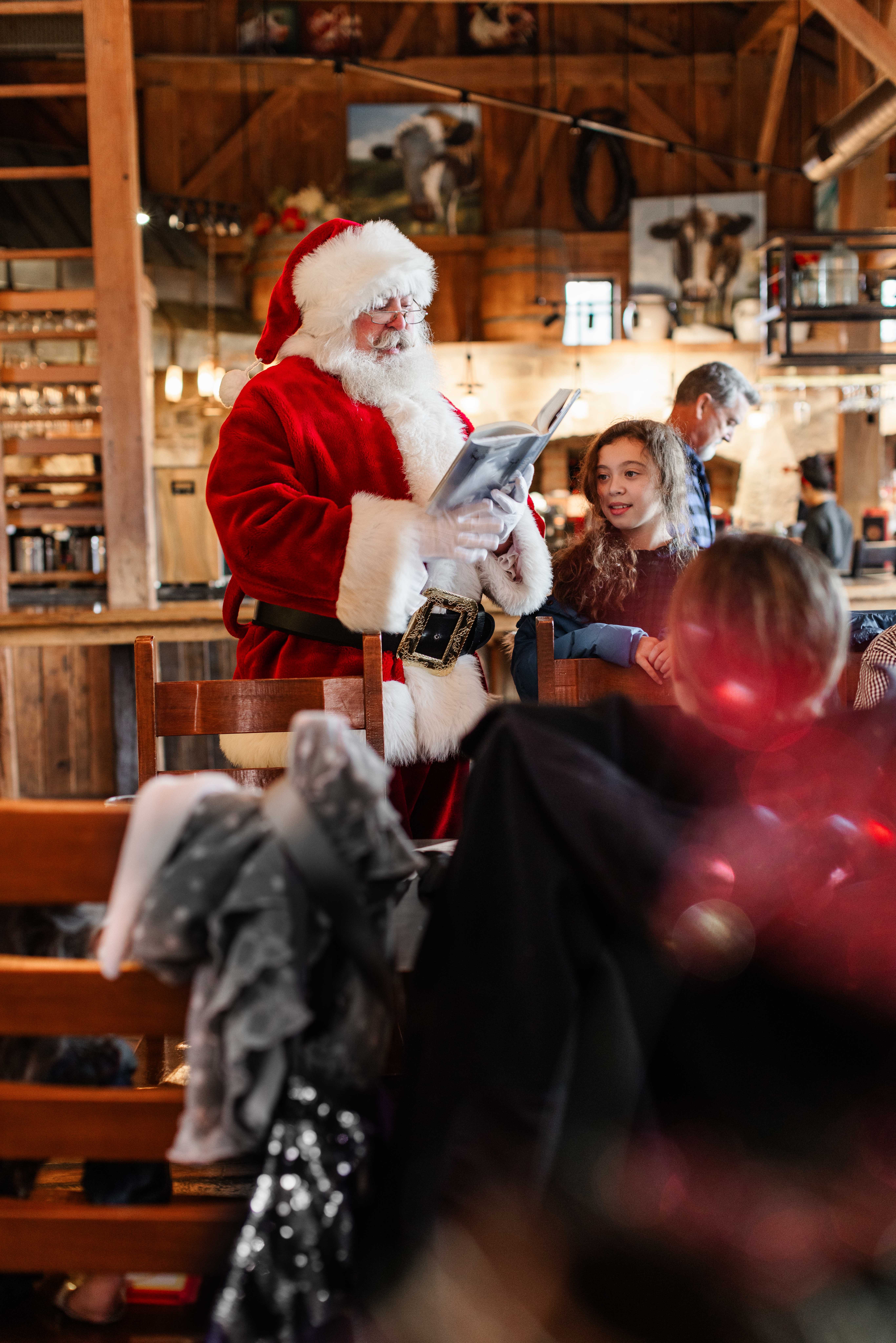 A photo of a Santa reading a book at Lunch with Santa at Gervasi.