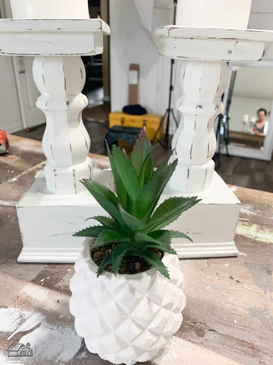 White wood candelabras and green succulent in white vase.